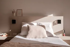 A serene, minimalist bedroom featuring soft textiles and wooden elements.