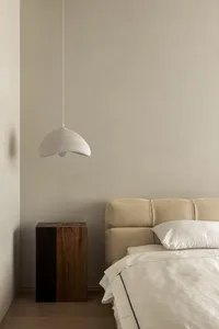 A minimalist bedroom featuring a textured lamp hanging above the bed.