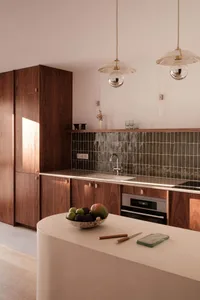 A modern kitchen with wooden cabinets, a marble countertop, and a backsplash of dark tiles.