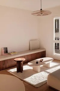 Modern minimalist living room featuring marble and wooden furniture, with a concrete floor and white rug.
