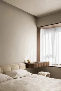 Minimalist bedroom featuring a bed with white linens and a wooden floating desk by the window.