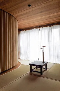 A minimalist room interior with bamboo mats, wood paneling, and fabric curtains.