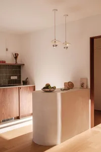 A minimalist kitchen with a concrete countertop and pendant lights.