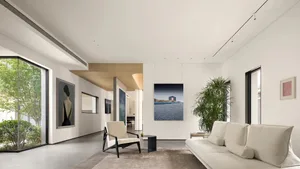 Minimalist living room with concrete tiles, white sofa, armchair, and framed artwork.