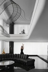 A modern black and white lobby interior featuring a suspended metal sculpture, a sleek black sofa, and a large window with ve