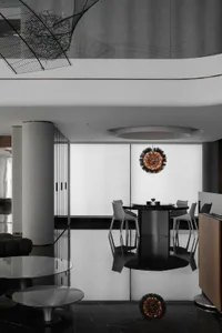 A modern dining room featuring a sleek, black marble table surrounded by modern white chairs with metallic accents.
