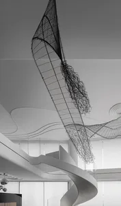 A modern metal sculpture hangs from the ceiling in an interior design setting.
