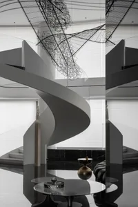 A modern interior space featuring a metal staircase with a wire sculpture hanging above it.