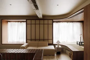 Contemporary living room with wooden paneled walls, white curtains, and a beige sectional sofa.
