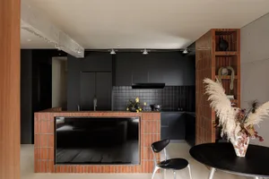 A modern residential kitchen with a brick wall and black cabinetry.