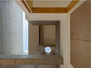 Modern interior with concrete walls and wooden accents, featuring a circular skylight and natural light.
