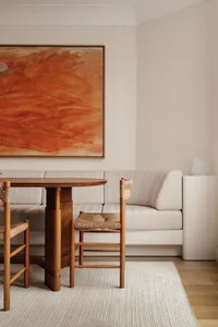 Modern cozy dining room featuring a wooden sofa, wooden chairs, and a round wooden table with a white rug on wood floor.