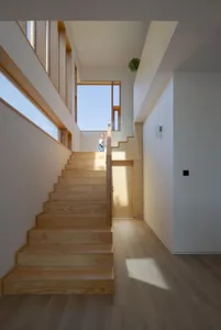 Modern interior design featuring a wooden staircase with large windows and natural light.