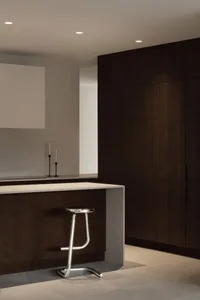 A modern kitchen with a stylish kitchen island featuring wooden cabinets and a sleek white countertop.