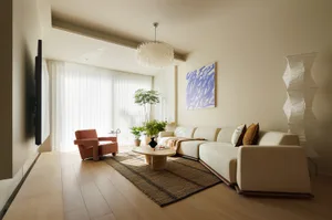 A modern living room featuring neutral-toned furniture and wood flooring.