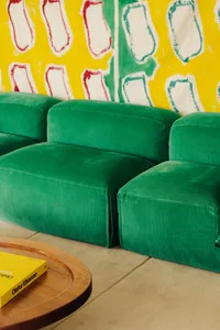 A modern, green corduroy velvet sofa in a contemporary living room setting.