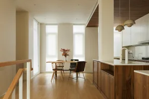 A modern kitchen featuring wooden cabinets, a dining table with chairs, and a wooden floor.