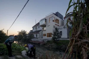 一棟現代住宅坐落於水岸旁，擁有大面玻璃窗與俐落當代設計。