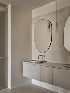 Modern bathroom with ceramic tiles, floating vanity, and round mirrors.