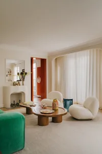 Modern living room with white and green furniture, wooden table, glass vase, and large windows