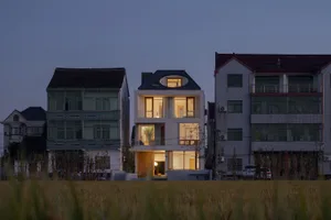 A modern residential house with large glass windows and doors.