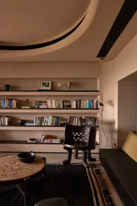 A modern industrial living room featuring concrete walls and flooring with minimalist furniture and art.