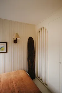 A minimalist bedroom featuring a wooden board and a bed with an orange blanket.