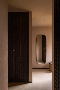 A minimalist interior design with a brown room featuring wooden doors and a mirror.