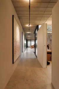 Modern minimalist interior with concrete tiles, white walls, and geometric lighting fixture.