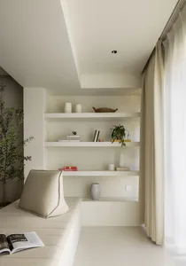 A minimalist living room with neutral-toned fabrics and a comfortable seating area next to a bookshelf.