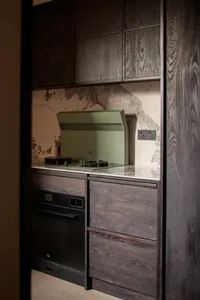Kitchen with dark wooden cabinets, a green hood, and a black oven.