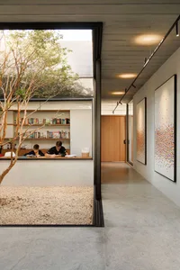 A modern home office space with concrete and glass elements, featuring two individuals working at a desk.