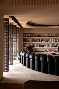 A modern living room featuring black leather upholstered furniture and a collection of books on shelves.