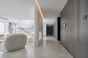 Modern living room with marble floating staircase and black wood cabinets on white marble floor.