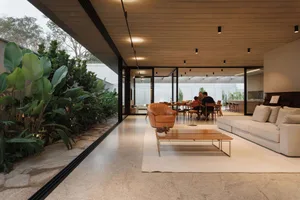 Modern living room with concrete floor, minimalist furniture, and large glass windows.