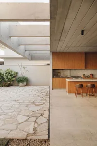 A modern patio featuring concrete flooring and a concrete staircase with greenery in the background.
