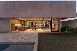 A contemporary residential interior with a modern, minimalist design featuring a concrete wall and open living space.