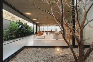 Modern villa interior with a minimalist design featuring concrete and wood materials, expansive glass walls, and natural land