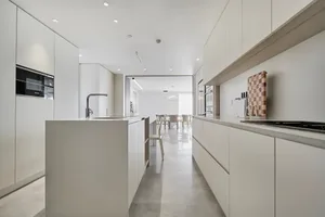 A modern kitchen with sleek, white cabinetry and a center island.