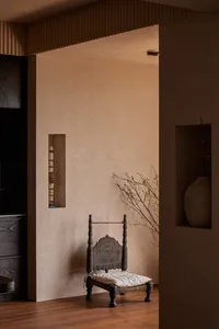 An interior design photo showcasing a rustic, wood-frame chair in a simple, minimalist setting.