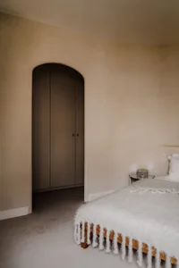 A modern bedroom featuring a bed with a woven blanket and wooden frame.