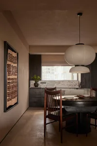 A modern dining room with black wooden furniture and a hanging light fixture.