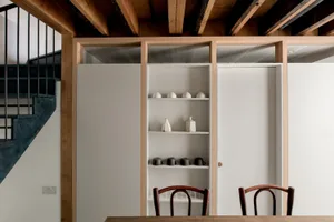 Modern kitchen featuring wooden shelves and minimalist chairs, designed for functionality and style.