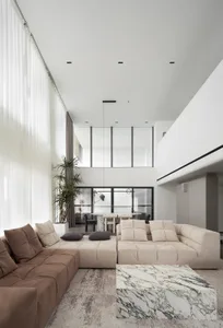 Modern minimalist living room with leather sofas, marble coffee table, and glass windows