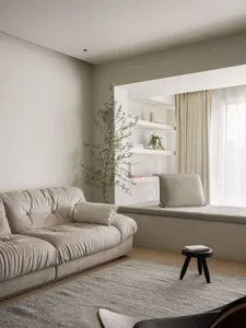 Minimalist living room with neutral-colored furniture, a large window, and a small stool.