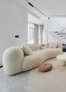 A modern living room with a textured sofa, round ottoman, and minimalistic design.