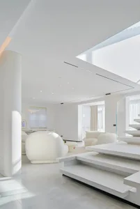 A modern, white living room with glass walls and a white sofa.