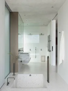 Modern minimalist bathroom featuring concrete, glass, and terrazzo elements.