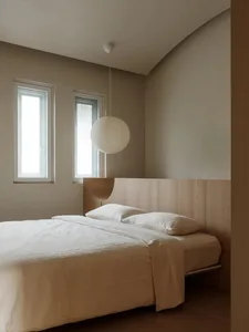 Minimalist bedroom featuring a bed with wood paneling and a spherical lamp hanging from the ceiling.