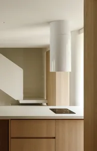 Modern, minimalist kitchen with wooden cabinets and white countertop and backsplash.